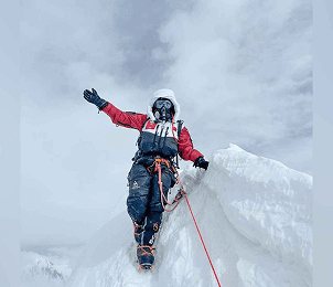 Expedition team standing before snow-capped Himalayan peaks