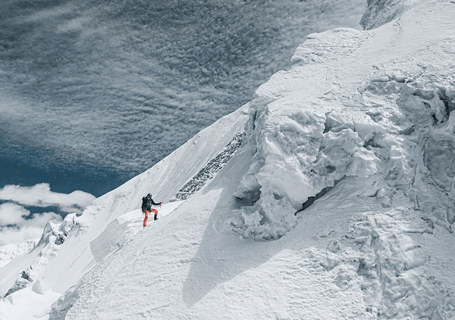 Mountaineer ascending a pristine snow ridge with an ice axe toward towering Himalayan peaks